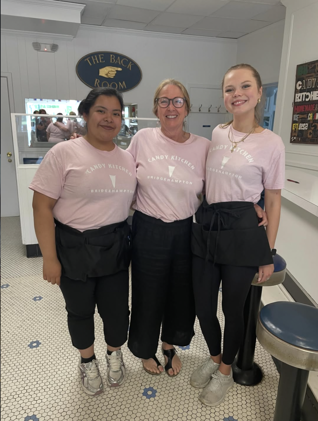 Candy Kitchen staff in pink Bridgehampton tees by The Back Room sign