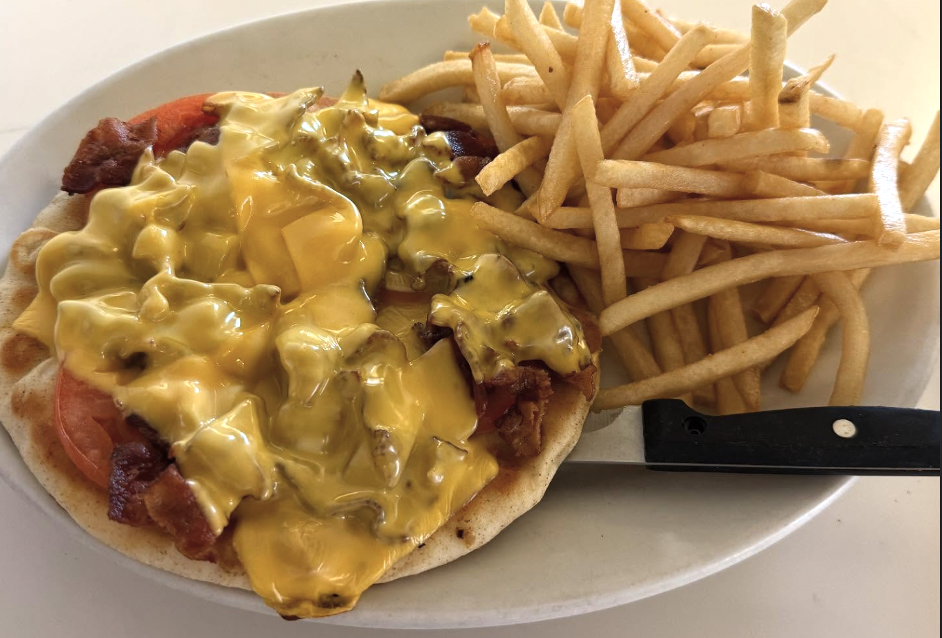 Open-face grilled cheese, ham and tomato on pita with a heap of golden fries